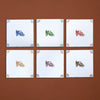 Six white tiles with colorful castle designs on a brown background