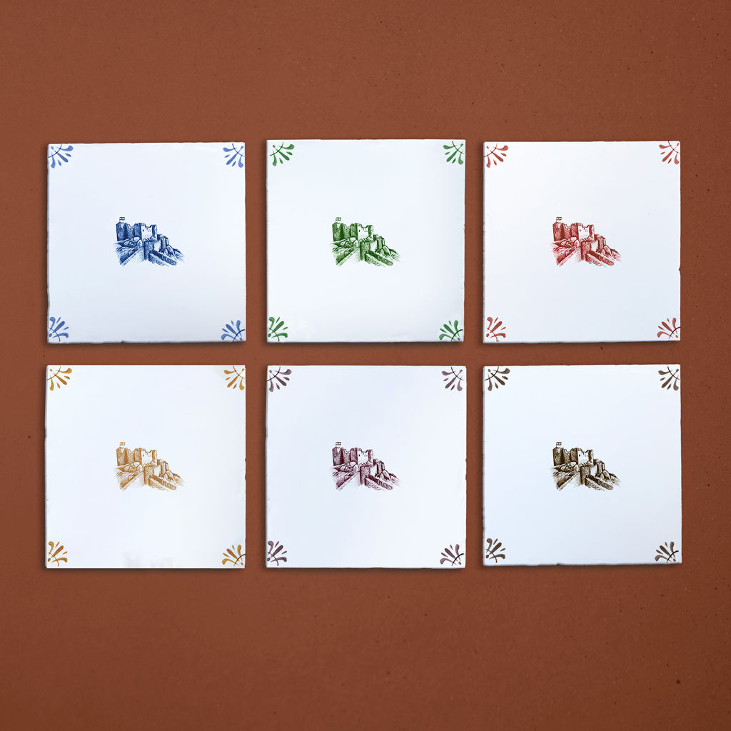 Six white tiles with colorful castle designs on a brown background