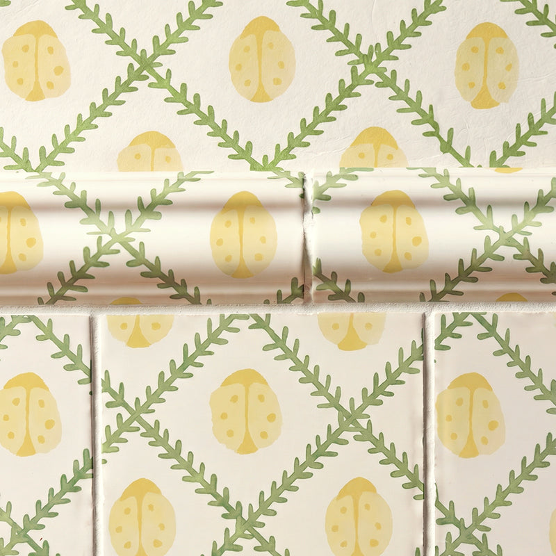 Patterned tiles and wallpaper with yellow ladybirds and green leaves on a beige background