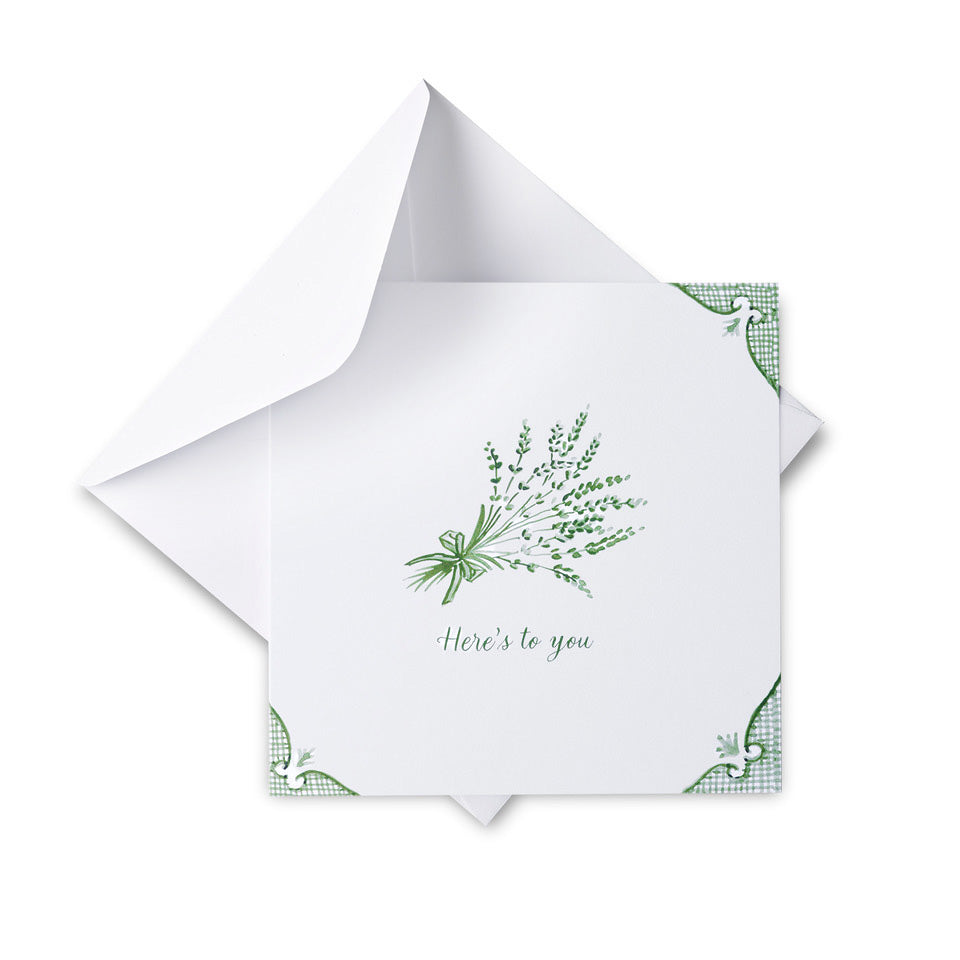 White card with green floral design and text 'Here's to you' on a white background